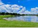 Scenic view of a community pond with a dock, blue sky, and fluffy white clouds at 106 Southern Pine Way, Davenport, FL 33837