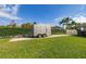 View of the backyard with a trailer parked on a paved area, surrounded by a well-maintained lawn at 10919 Lakeshore Dr, Clermont, FL 34711