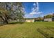 Large backyard with lush green lawn, shed, and trailer parked on a gravel pad at 10919 Lakeshore Dr, Clermont, FL 34711