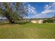 Backyard featuring a large tree providing shade, a storage shed, and view of the lake at 10919 Lakeshore Dr, Clermont, FL 34711