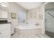 Bathroom featuring a soaking tub, glass shower, and granite countertop with white cabinets at 10919 Lakeshore Dr, Clermont, FL 34711