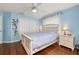 Cozy bedroom featuring blue walls, wood floors, ceiling fan, and a white finish on furnishings at 10919 Lakeshore Dr, Clermont, FL 34711