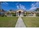 Beautifully landscaped front yard with lush green grass, and palm trees leading to the front entrance at 10919 Lakeshore Dr, Clermont, FL 34711