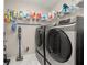 Modern laundry room with tile floors featuring new washer and dryer units and shelving at 10919 Lakeshore Dr, Clermont, FL 34711