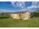 Backyard view of a storage shed with decorative vines, surrounded by green grass and blue sky at 10919 Lakeshore Dr, Clermont, FL 34711