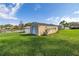 View of a storage shed in the backyard with a roll-up door and decorative plants around the perimeter at 10919 Lakeshore Dr, Clermont, FL 34711