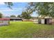 A spacious backyard with green grass, sheds, and a wooden fence at 1506 Maryland Ave, St Cloud, FL 34769