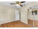 Bedroom featuring wood-look floors, a ceiling fan, closet with mirrors, and an adjacent bathroom at 1506 Maryland Ave, St Cloud, FL 34769