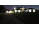 Night shot of a well-lit two story home with manicured lawn, long driveway, and a detached garage at 15350 Arabian Way, Montverde, FL 34756