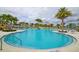 Large swimming pool with sun loungers and umbrellas, surrounded by lush palm trees at 1696 Tropical Palms Cir, Kissimmee, FL 34747