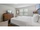 Bright bedroom with white king bed, wood dresser, and natural light from two large windows at 1909 Nice Ct, Kissimmee, FL 34747