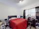 Bedroom featuring a bed with a red comforter, a desk area, and simple decor at 1921 N Forsyth Rd, Orlando, FL 32807