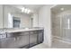 Bathroom featuring dark cabinets with granite countertop, dual sinks, a large mirror, and a glass door shower at 2471 Dubai St, Kissimmee, FL 34747