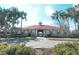 Exterior shot of community clubhouse featuring a red roof, tan stucco, and tropical landscaping at 2512 Volta Cir, Kissimmee, FL 34746