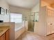 Relaxing main bathroom features a garden tub, glass-enclosed shower, and neutral tiling at 2577 Aster Cove Ln, Kissimmee, FL 34758