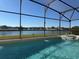 The screened-in pool overlooks a tranquil lake and green lawns at 2577 Aster Cove Ln, Kissimmee, FL 34758