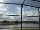 View of a lake surrounded by green grass and houses, seen from a screened-in patio at 2577 Aster Cove Ln, Kissimmee, FL 34758