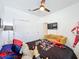 Bright bedroom with a ceiling fan, black padded headboard, grey carpet, yellow couch, and a mounted tv at 281 Piave St, Haines City, FL 33844