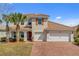 Charming two-story home featuring a brick driveway, tile roof, and an attached two-car garage at 3723 Isles Arbor Ln, Kissimmee, FL 34746