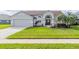 Single-story home with manicured lawn, two-car garage, and a welcoming entryway at 4119 Maidu Ct, St Cloud, FL 34772