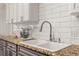 Close-up of a kitchen sink featuring a faucet and sleek granite countertops with white subway tile backsplash at 4815 Cypress Dr, Lake Wales, FL 33898