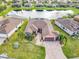 Aerial view of home with lake, lush landscaping and a paved driveway leading to a two-car garage at 484 Villa Park Rd, Kissimmee, FL 34759