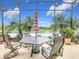 Outdoor patio set with table and chairs, under a screen enclosure, overlooking a serene lake and palm trees at 484 Villa Park Rd, Kissimmee, FL 34759