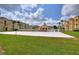 Community sand volleyball court with lush green grass in front of Mediterranean-style buildings under a partly cloudy sky at 501 Terrace Ridge Cir # 501, Davenport, FL 33896