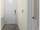 Hallway view with a white front door, thermostat, and a peek into the adjacent bathroom at 5560 Metrowest Blvd # 304, Orlando, FL 32811