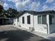 Side of the home featuring white siding, black roof, and a carport at 610 Illinois Ave, St Cloud, FL 34769