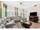 Comfortable living room with gray sofa, tile flooring, modern ceiling fan, and natural light at 7503 Mourning Dove Cir # 301, Reunion, FL 34747