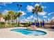 Relaxing hot tub surrounded by lush greenery and palm trees under a blue sky at 7622 Oakmoss Loop, Davenport, FL 33837