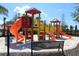 Community playground featuring slides, climbing structures, and a bench at 7622 Oakmoss Loop, Davenport, FL 33837