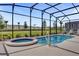 A screened in in-ground pool and attached spa with lounge chairs in a grassy backyard at 7622 Oakmoss Loop, Davenport, FL 33837