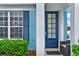 Charming turquoise house featuring a blue door, white trim, a manicured bush, and a window at 7682 Fitzclarence St, Kissimmee, FL 34747