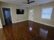 Bright living room features gleaming hardwood floors, ceiling fan, and a wall mounted television at 7709 Bell Blvd, Orlando, FL 32810