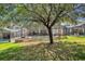 An exterior shot of the backyard with a screened-in pool and spa, along with mature landscaping at 7761 Tosteth St, Kissimmee, FL 34747