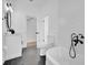 Bathroom with a black tile floor, white wainscoting, vintage bathtub with shower and vanity with black framed mirror at 802 S 10Th St, Haines City, FL 33844