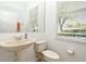 Well-lit half bathroom with a pedestal sink, toilet, and window at 8766 The Esplanade # 23, Orlando, FL 32836