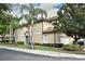 A two-story tan townhome featuring a tile roof, attached garage, and lush landscaping at 8766 The Esplanade # 23, Orlando, FL 32836