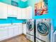 Bright laundry room featuring white cabinetry, modern washer and dryer, and colorful decor at 885 Spring Park Loop, Celebration, FL 34747