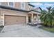 A tan two-story home featuring a garage and front porch with brick pillars, offering curb appeal at 1894 Valley Forge Dr, St Cloud, FL 34769