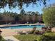 Outdoor community pool with lounge chairs surrounded by lush landscaping and brick pool deck at 10210 Hartford Maroon Rd, Orlando, FL 32827