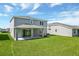 Backyard with a spacious lawn, covered porch, and exterior elevation of the home at 1111 Olivine Ave, Dundee, FL 33838