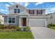 Two-story house with a gray exterior, red shutters, landscaped front yard, and a two car garage at 1111 Olivine Ave, Dundee, FL 33838