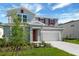 Two-story home featuring a two-car garage, a red front door, well-maintained lawn and landscape, and light gray paint at 1111 Olivine Ave, Dundee, FL 33838
