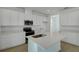 Modern kitchen featuring white cabinets, stainless steel appliances, a quartz island, and wood-look tile flooring at 1111 Olivine Ave, Dundee, FL 33838