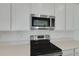 Close-up of new stainless steel oven and microwave, quartz countertops, and sleek white cabinets at 1111 Olivine Ave, Dundee, FL 33838
