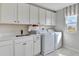 Modern laundry room with white cabinetry, sink, counter space, and front-loading washer and dryer at 1111 Olivine Ave, Dundee, FL 33838