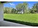 Expansive backyard with lush green grass and mature trees beyond the patio at 1115 Olivine Ave, Dundee, FL 33838